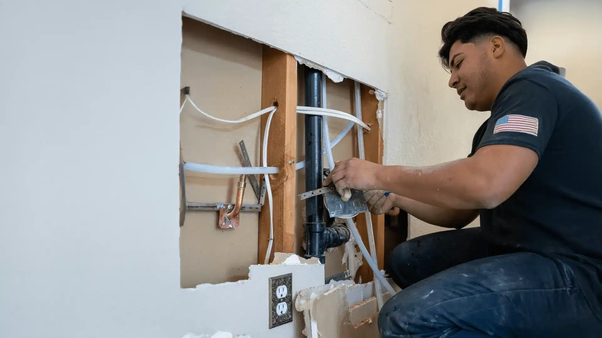 technician repairing plumbing pipes inside an open wall during a home renovation