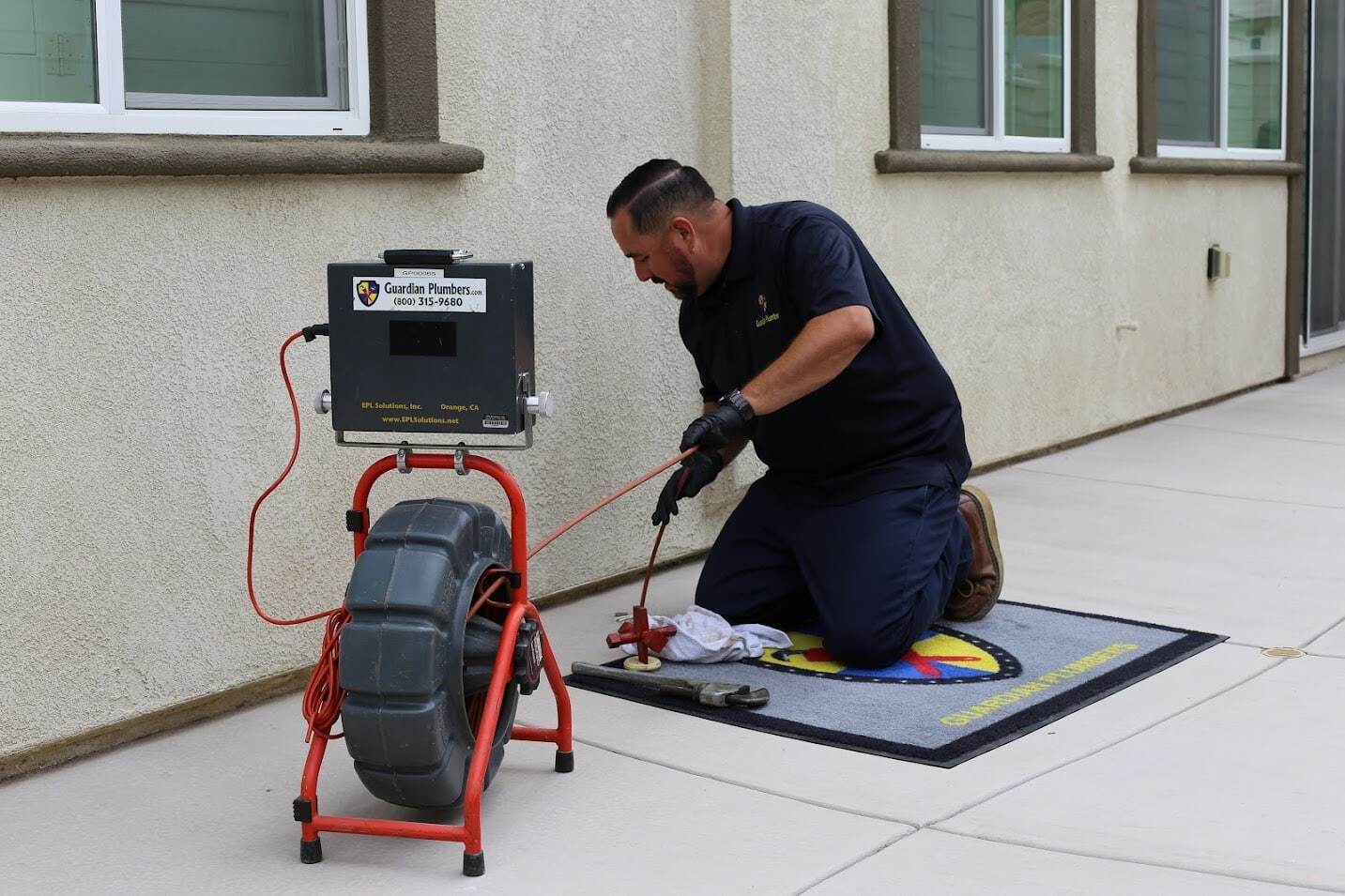 A Guardian Plumbers, Heating, Air & Electrical technician carefully operates a sewer camera inspection, focused intently on the drain. The sophisticated equipment and the technician's professionalism highlight the thorough and advanced services offered by Guardian Plumbers, Heating, Air & Electrical, ensuring home plumbing systems are in top shape.