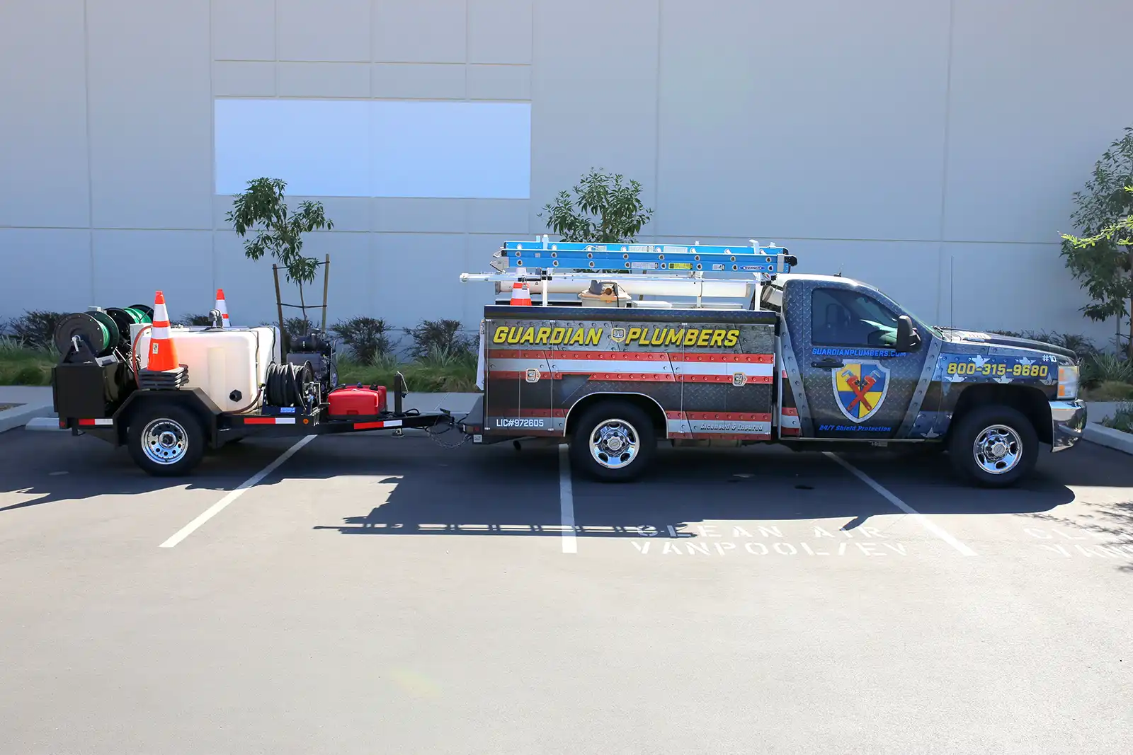 A Guardian Plumbers truck, proudly displaying the company logo, is seen pulling a hydro jetter. The setup is ready to clear buildup in drains, showcasing the advanced equipment and professional capability of Guardian Plumbers to handle tough plumbing issues efficiently.
